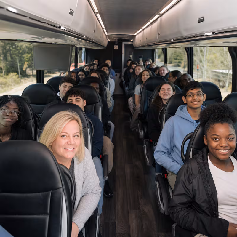 Group boarding a white charter bus for School Transportation transportation in St Paul