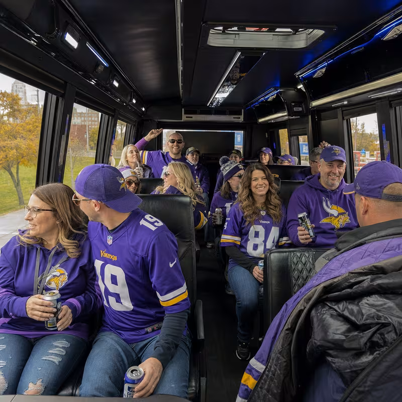 Group boarding a white charter bus for Sporting Event Transportation transportation in St Paul